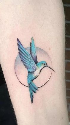 a small tattoo on the arm of a woman with a hummingbird flying over it