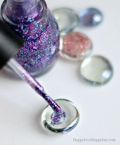 the nail polish is purple and has glitter on it, as well as three other colors