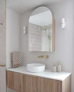 a white sink sitting under a bathroom mirror next to a wooden cabinet and counter top