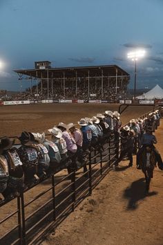 a group of people riding on the backs of dirt bikes in front of a fence