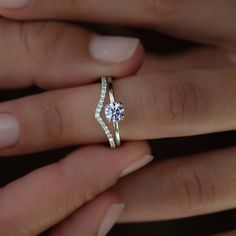 a woman's hand with a diamond ring on top of her finger and an engagement band