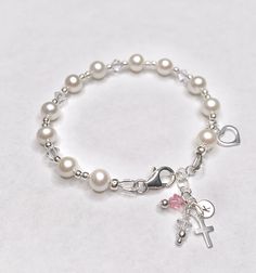 This lovely First Communion bracelet features real pearls and Swarovski crystals. This bracelet is sure to be the perfect gift! Each First Communion bracelet is made with sterling silver elements and includes a sterling silver cross and heart charm. Make it extra special by personalizing it with a sterling silver hand-stamped initial charm and birthstone. Makes an ideal gift for Baptism, First Communion, Confirmation, Easter, Flower Girls, Maid-of-Honor, Bridesmaids, Mother-of-the-Bride, Godmoth Adjustable Pearl Bracelet For First Communion, Pearl Charm Bracelet For First Communion, Adjustable Pearl Charm Bracelet For First Communion, Adjustable Pearl Bracelet With Charm For First Communion, Adjustable Pearl Bracelets For Baptism, Communion Gifts Girl, Real Pearl Bracelet, First Communion Gifts, Swarovski Crystal Bracelet