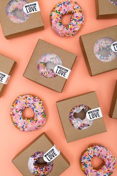 donuts with love written on them are displayed in boxes and decorated with sprinkles