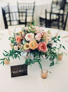 a bouquet of flowers is sitting on top of a table with candles and place cards