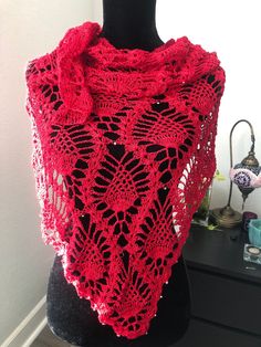 a red knitted shawl sitting on top of a mannequin