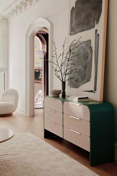 a living room filled with furniture and a painting hanging on the wall above it's doorway