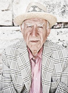 an old man wearing a straw hat and plaid shirt