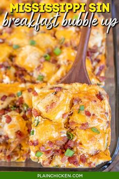 a casserole dish with cheese, bacon and green onions in it on a wooden spoon