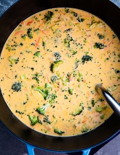 broccoli and cheese soup in a black pan with a spoon on the side