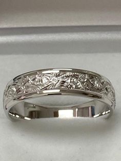 a wedding band with an intricate design on the inside and outside, in white gold