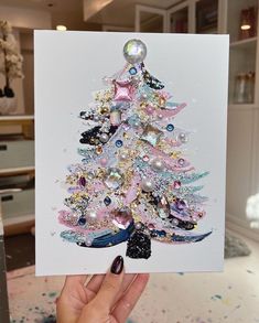 a person holding up a card with a christmas tree on it