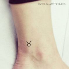 a small tattoo on the ankle of a woman's left foot, with an zodiac symbol