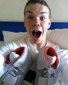 a young man with his mouth wide open holding two pairs of shoes in front of him