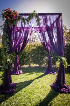 an outdoor wedding setup with purple drapes and flowers