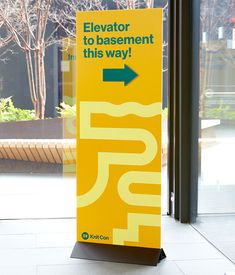 a yellow sign with an arrow pointing to the right in front of a glass door