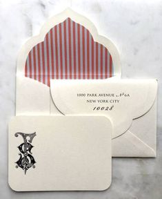 two envelopes with red and white stripes on them, one has a monogrammed letter