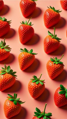 many strawberries are arranged on a pink surface