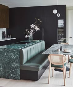 a kitchen with marble counter tops and green chairs in front of a bar area that has flowers on it