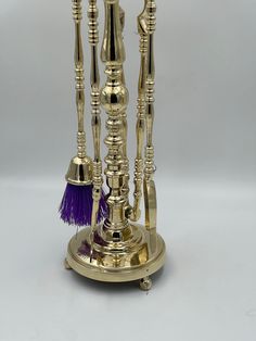 an ornate brass candle holder with purple tassels and candlesticks on it