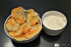 potato chips and dip in a bowl on a black counter top with a small white container