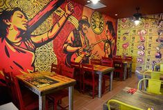 the interior of a restaurant with brightly colored walls and tables, chairs, and artwork on the wall