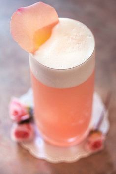 a pink drink with a flower on the top is sitting on a small saucer