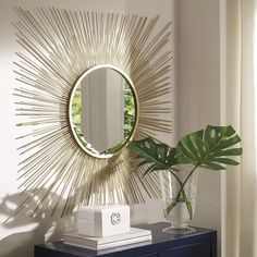 a mirror on the wall next to a dresser with a plant in front of it