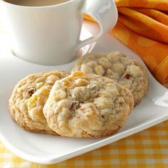 two cookies and a cup of coffee on a white plate next to orange napkins