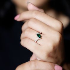 a woman's hand holding an emerald ring