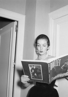 an old photo of a woman reading a ballet program book in front of a door