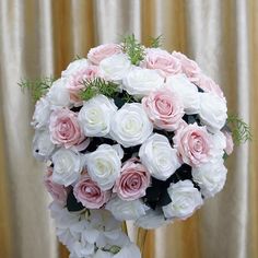 a bouquet of white and pink roses in front of a curtain