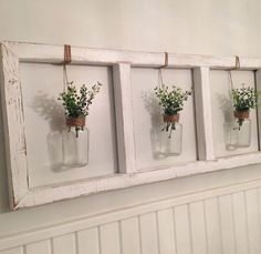 four mason jars with flowers are hung on the wall