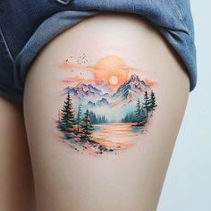 a woman's thigh with a mountain scene tattoo on it