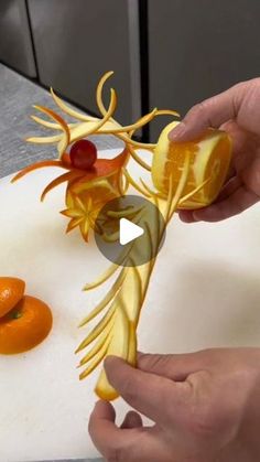 someone is carving an orange flower on a cutting board with other fruit in the background