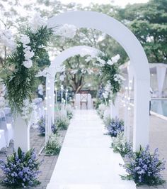 an outdoor wedding ceremony with white flowers and greenery on the aisle, along with blue hydrangeas