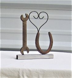 a metal hook with a heart and a wrench on it sitting on a table