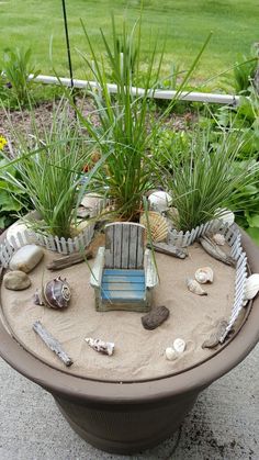 a small chair sitting on top of a table covered in sand and sea shells with plants growing out of it