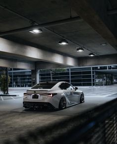 a white sports car parked in an empty parking garage