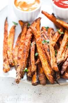 baked french fries on a plate with dipping sauces