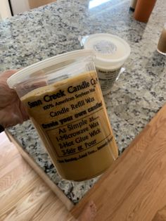 a person holding up a plastic cup filled with liquid on top of a countertop