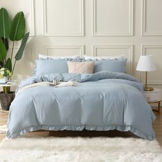 a bed with blue comforters and pillows in a room next to a white rug