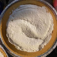 there is a pie with white frosting in the pan on the table next to some soda cans