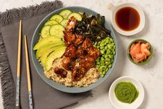 a blue plate topped with rice, meat and veggies next to dipping sauce