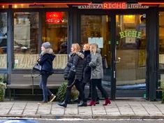 three women walking down the sidewalk in front of a restaurant