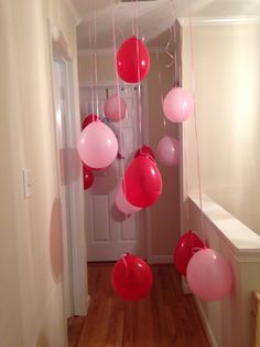 red and pink balloons are hanging from the ceiling in this hallway decorated with white trim