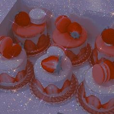 there are many small cakes with strawberries on the top one is red and white