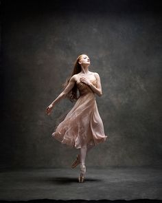 a woman in a dress is dancing with her arms outstretched and head tilted to the side