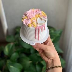 a person holding a cake with flowers on it