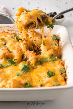 a casserole dish with cheese and vegetables being lifted from the casserole