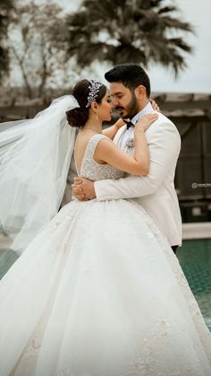 a bride and groom embracing each other in front of palm trees